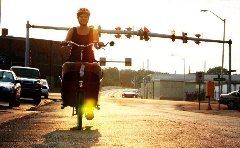 woman riding cargo bike in a city