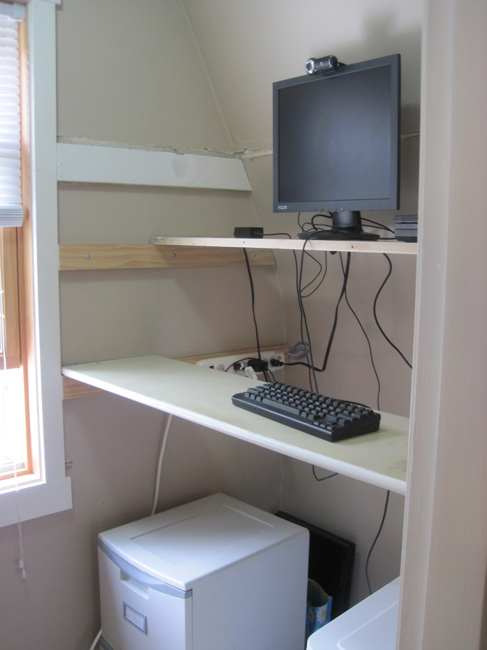 Slats across the close form shelves for a keyboard and monitor in a closet