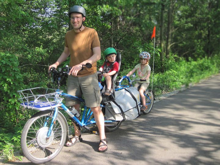 Me with a cargo bike and two kids riding on the bike. 