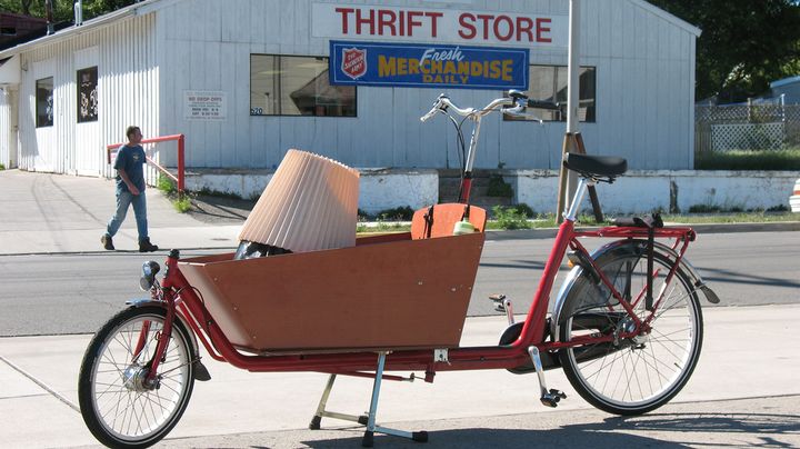 Bakfiets loaded with items parked in front of a thrift store