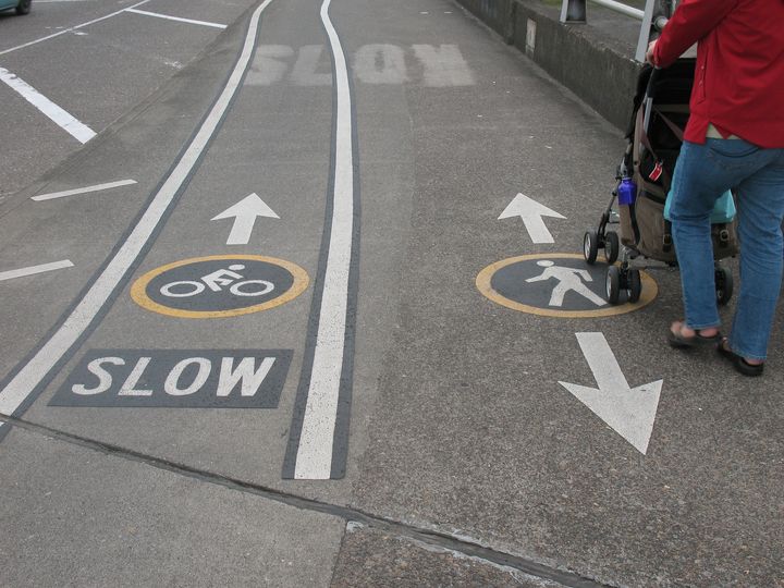Photo of sidewalk with "slow" bike lane marked